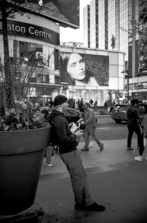 A man relaxing in front of Eaton Centre, the face on the billboard in the back creates an interesting relation (I think
